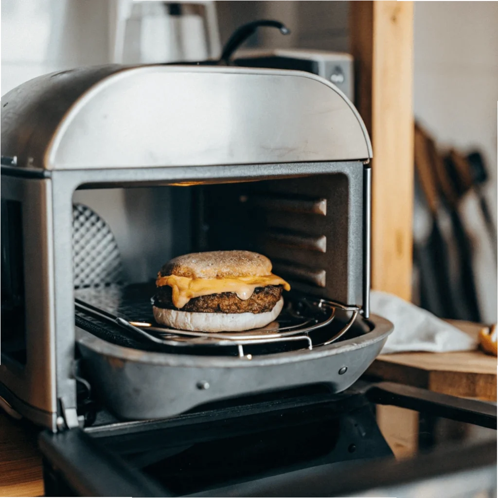 A breakfast sandwich with a crispy patty and melted cheese inside an air fryer.