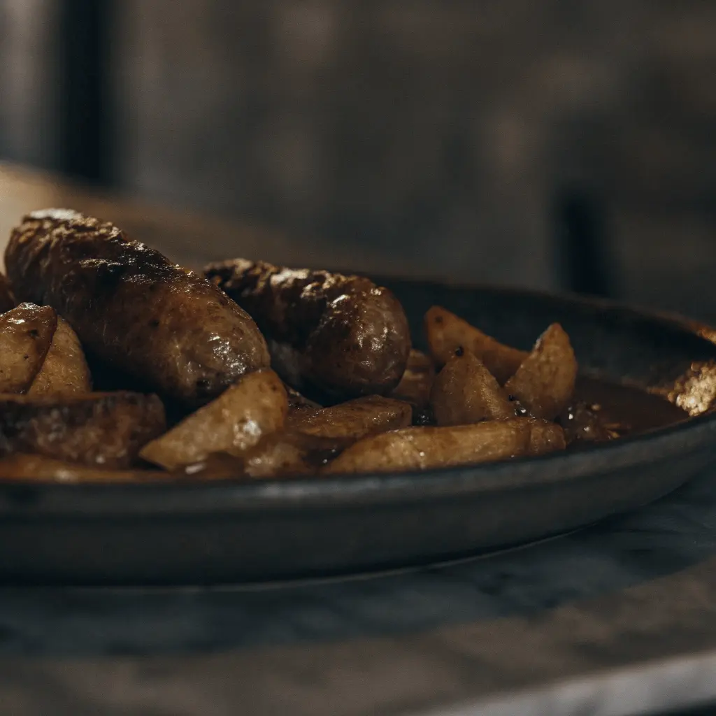 A plate of smothered potatoes and sausage served with a rich sauce and golden-brown potatoes.