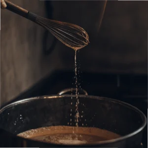 Medium saucepan on a stove with sugar, corn syrup, and butter inside.